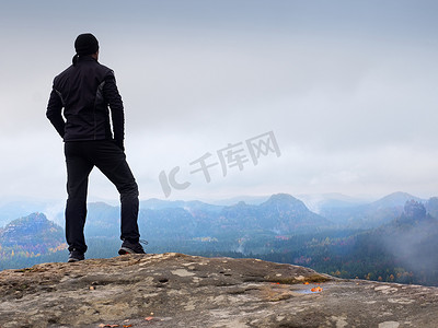 岩石公园陡峭悬崖上的徒步者注视着浓雾