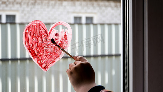 一个女孩的手，用画笔在窗户上画红心，复制文字空间，待在家里