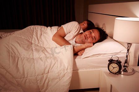宿醉摄影照片_男人在床上失眠，晚上在卧室里有偏头痛、压力、失眠、宿醉