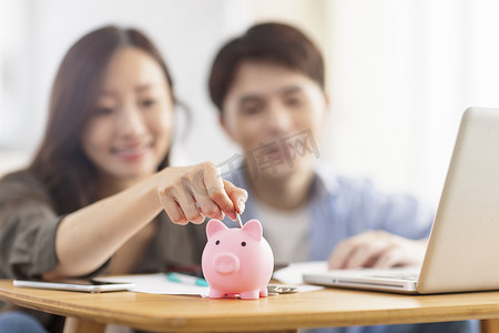 幸福的夫妻在存钱罐中插入硬币。家​​庭财务。专注于存钱罐。