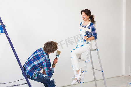 装修壁纸摄影照片_团队合作、翻新和维修概念 — 坐在梯子上涂着油漆的男人和女人