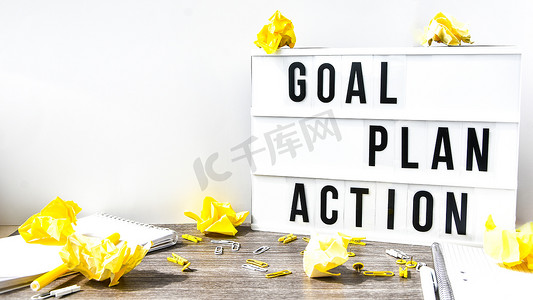 goal摄影照片_木制背景上带有文字 GOAL PLAN ACTION 的灯箱、复制空间、皱巴巴的黄纸、办公用品
