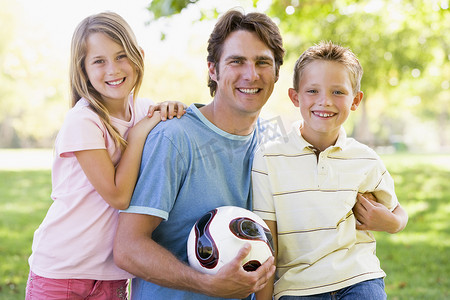 气排球幕布摄影照片_男人和两个小孩在户外打排球微笑