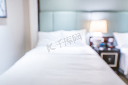 现代双人床摄影照片_干净舒适的现代酒店卧室内部配有双人床，抽象的散焦模糊与散景背景，豪华旅行的设计理念。