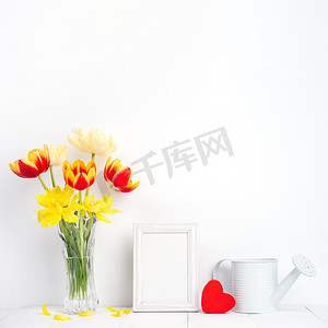 玻璃花瓶中的郁金香花，相框放在白色木桌背景上，与家里干净的墙壁相映成趣，特写，母亲节装饰概念