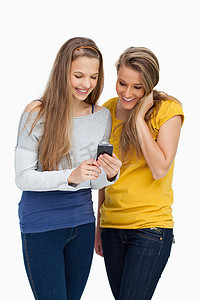 两名女学生一边看手机一边微笑
