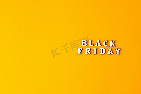 黄色背景前的木制字母文本黑色星期五、复制空间、横幅顶视图平躺季节性销售、零售、购物概念
