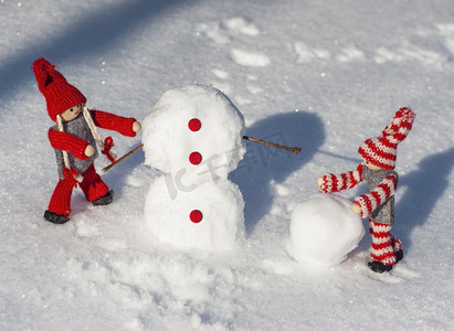 穿红色针织衣服的木娃娃滚下雪球来建造