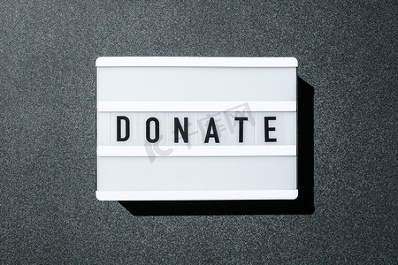 黑色背景上的灯箱板，上面写着黑色字母的捐赠字样。