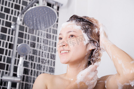 快乐的女人用洗发水和淋浴洗头