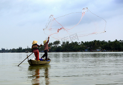 柬埔寨渔民摄影照片_两名渔民在小船上用网捕鱼