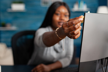 签手摄影照片_非洲裔美国学生在远程工作的电脑上贴便签