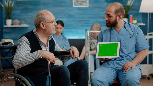 老病人摄影照片_男护士和老病人看着平板电脑上的绿屏
