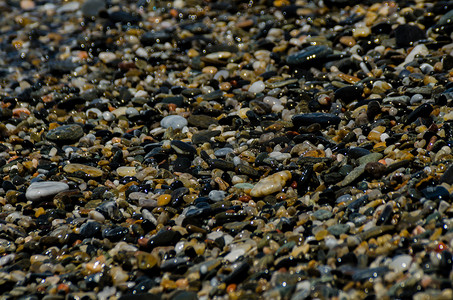 蓝色海浪装饰摄影照片_海浪冲刷的卵石滩，形成海岸的各种小石头