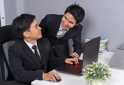 两个商人在使用笔记本电脑时大笑