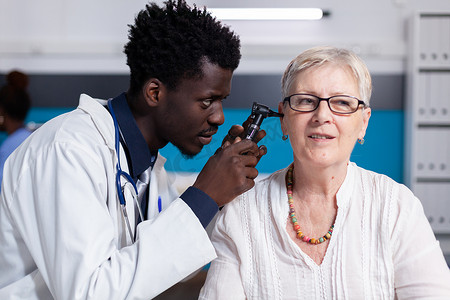 黑人年轻医生在老年患者身上使用耳镜