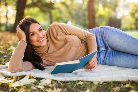 女人在公园看书，在秋天享受