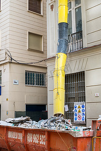 一座正在装修的建筑附近装满垃圾的垃圾箱