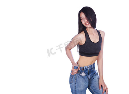 成功减肥摄影照片_女人展示了她的减肥效果，穿着白色背景中突显的旧牛仔裤