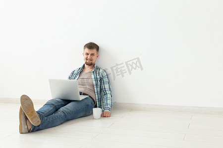 穿着休闲服的积极年轻人坐在空房间的地板上上网寻找新住所。