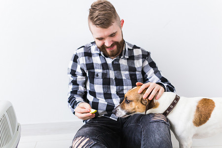 宠物主人摄影照片_狗携带包和宠物主人的概念 — 穿着格子衬衫的迷人开朗男性拥有最喜欢的宠物。