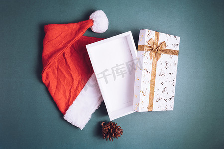在绿色背景上带有圣诞帽的空礼品盒的顶部视图。