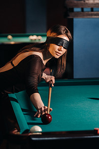 在台球俱乐部里，一个戴着眼罩、手里拿着球杆的女孩。俄罗斯台球