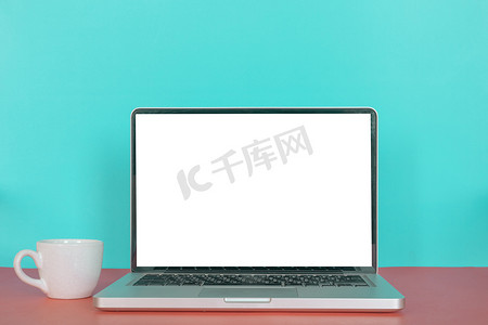 带空白屏幕的现代笔记本电脑，柔和色彩背景中的咖啡杯