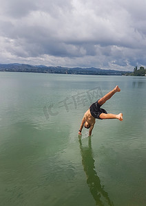 开心跳跃的小男孩摄影照片_小男孩喜欢跳入水中的机会。