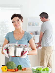 迷人的妻子拿着锅，而她的丈夫正在洗盘子