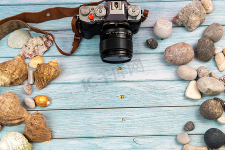 夏天主题背景摄影照片_蓝色木质背景上的相机和贝壳。海洋主题