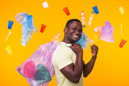 垃圾、塑料回收、污染和环境概念问题 — 黄色背景下携带垃圾袋的滑稽男子
