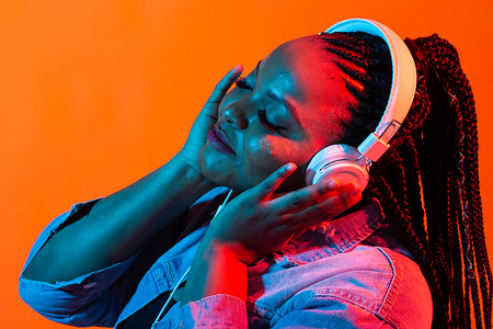年轻的非洲女人戴着耳机听音乐的霓虹画像。