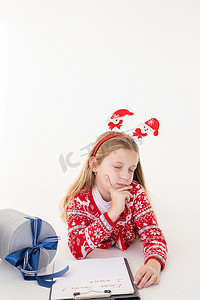 体贴的小女孩在白色背景上写信给圣诞老人。目标计划梦想为新年圣诞节概念做清单。