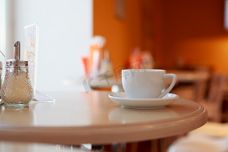 咖啡杯在咖啡厅的桌子上，背景模糊，白茶杯，早餐，咖啡厅背景橙色