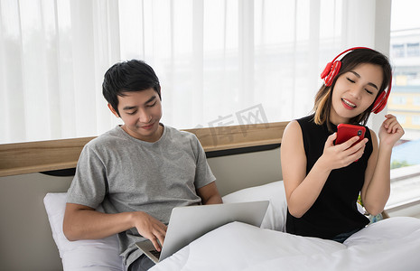 这对夫妇戴上耳机，在沙发上用手机听音乐，为了社交距离和自我责任理念，他们在屋里快乐地跳舞