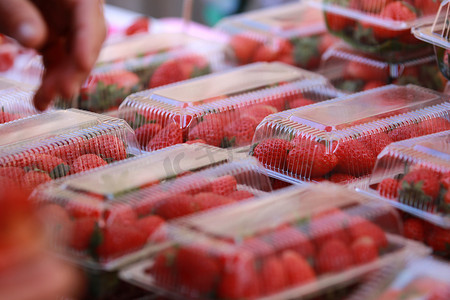 买家秀征集主图摄影照片_塑料包装中的草莓待售和买家的手选择购买草莓