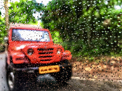 车窗上的雨滴，背景中汽车和森林的景色模糊