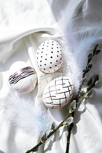 时髦的彩色时尚天然复活节彩蛋、羽毛、白色丝绸质朴布上的褪色柳枝。