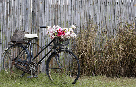 一辆生锈的旧自行车，自行车架上放着一束花