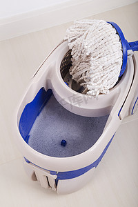 桶塑料摄影照片_用于清洁地板的拖把和蓝色桶的特写