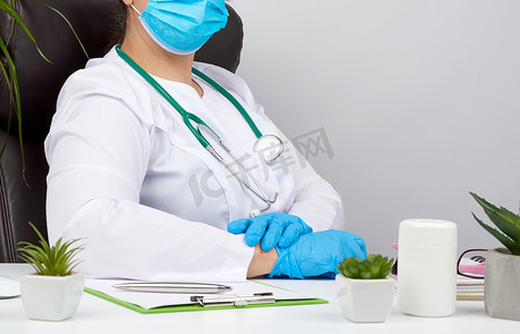 一件白色外套和蓝色乳汁手套的医生坐在白色 wor