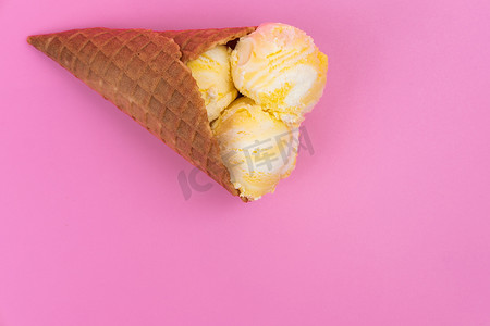 粉红色背景的华夫蛋筒中的水果香味冰淇淋球。