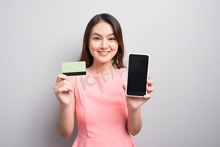 迷人的亚洲女性手持智能手机并展示信用卡