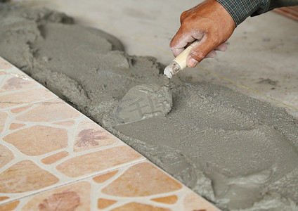 家杂摄影照片_杂工铺设瓷砖，用砂浆抹平