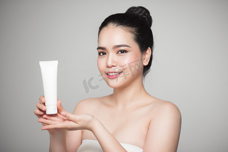 美丽的亚洲女人脸肖像拿着和展示奶油管产品