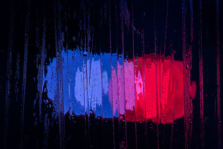 夜间警灯散景槽湿玻璃的抽象背景特写，有选择的焦点
