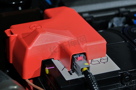 v电池摄影照片_带红色加号符号的电池正极塑料盖，电池放置在发动机舱内。