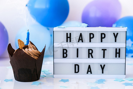带有文字“生日快乐”的灯箱和抽象的离焦模糊节日背景上的巧克力蛋糕蜡烛。