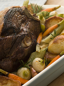 蒸羊腿摄影照片_烤春羊腿配烤土豆和蔬菜